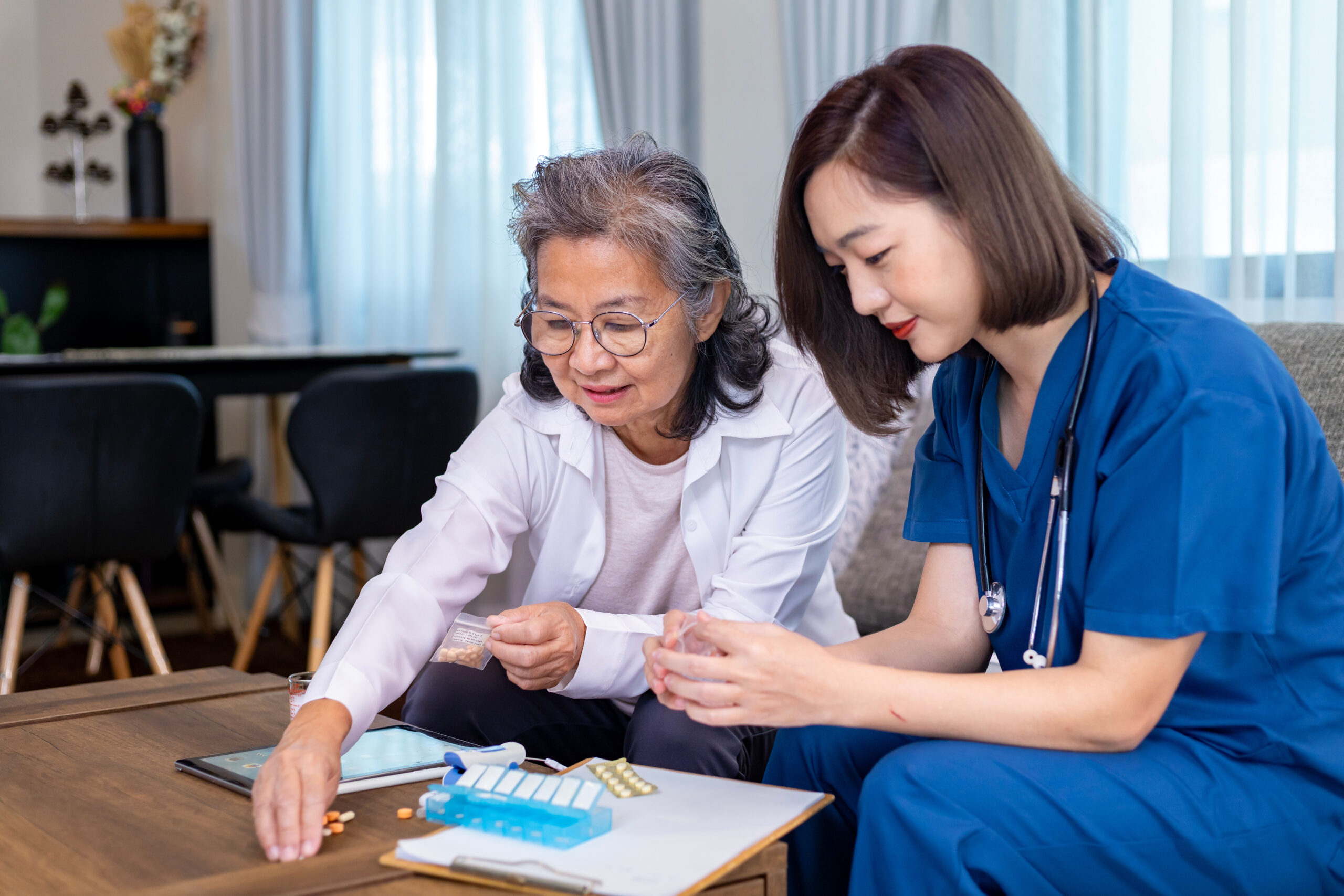 Senior woman get medical service visit from caregiver nurse at home while explaining on doses of vitamins and drug pill for health care and pension welfare insurance